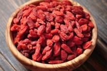 wooden bowl with goji berries on the table closeup